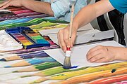 Kind malt mit Pinsel und Wasserfarben