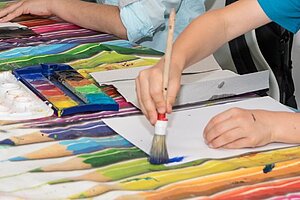 Kind malt mit Pinsel und Wasserfarben