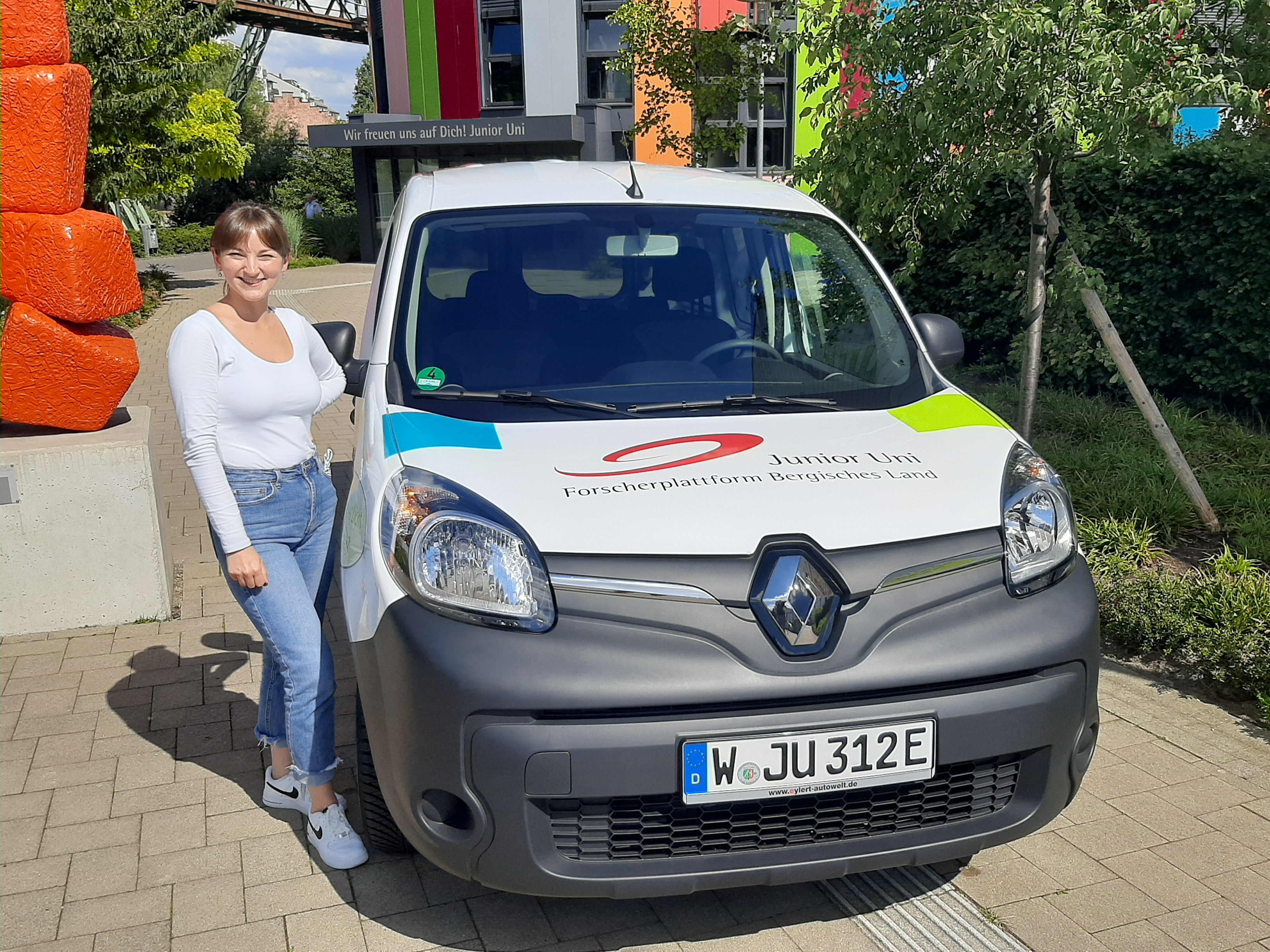 Aushilfkraft Anna Stojanow steht neben dem neuen Junior Uni-E-Auto
